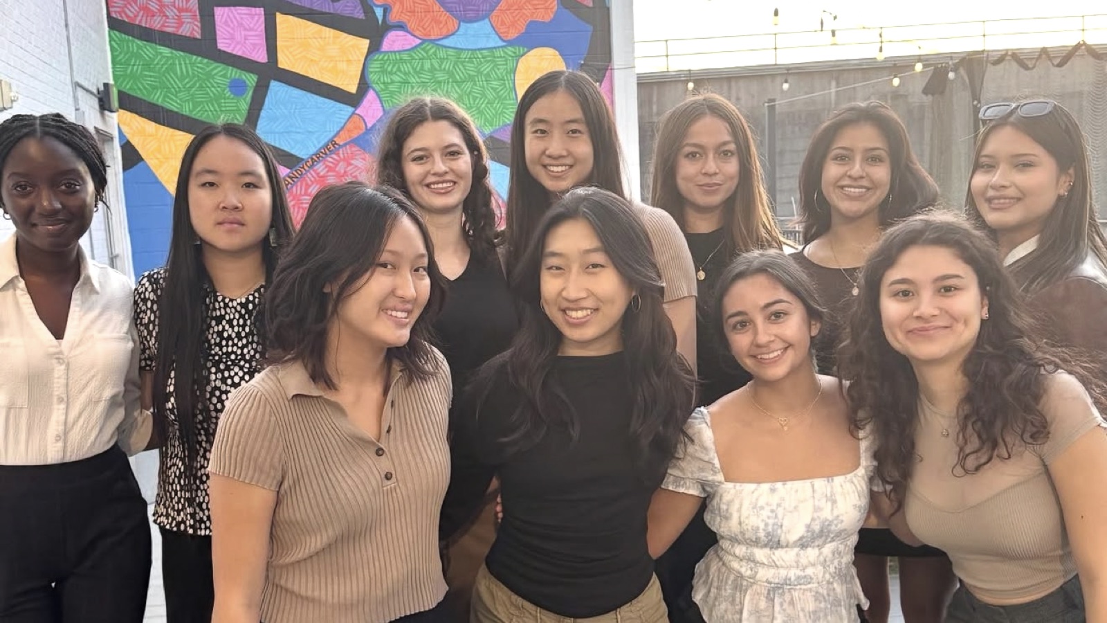 Girls Into VC members posing in front of a colorful mural